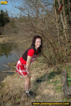 Outdoor pissing on the dry grass on a pond shore